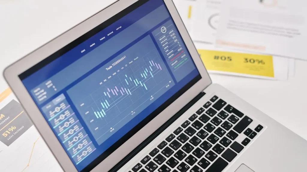 Laptop showing an SEO analytics dashboard next to printed marketing reports